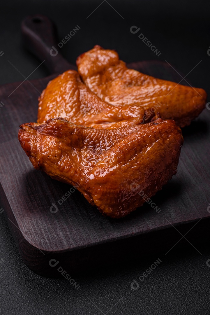 Deliciosas asas de frango grelhado com especiarias e ervas em um fundo escuro de concreto