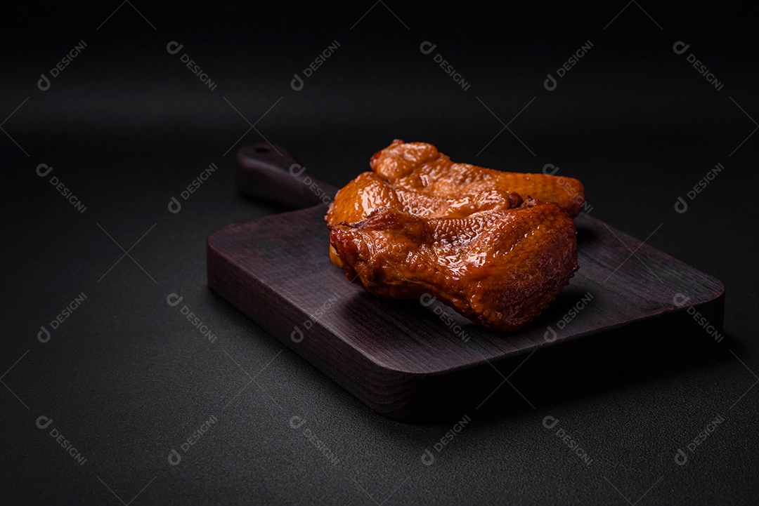 Deliciosas asas de frango grelhado com especiarias e ervas em um fundo escuro de concreto