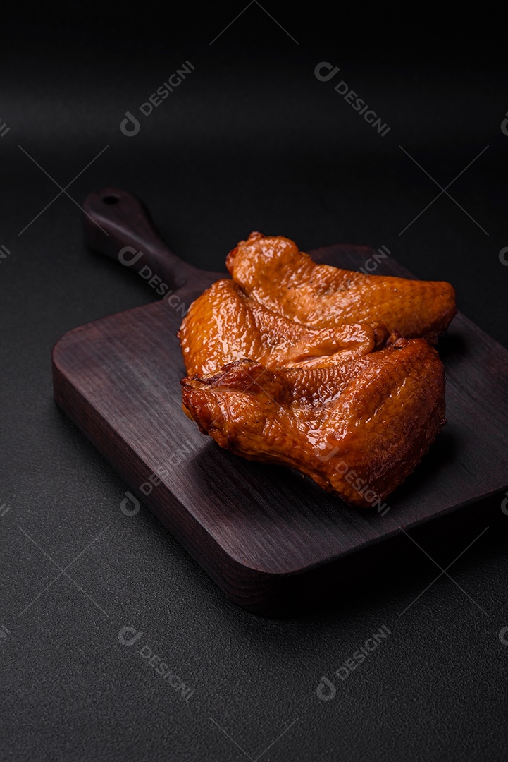 Deliciosas asas de frango grelhado com especiarias e ervas em um fundo escuro de concreto