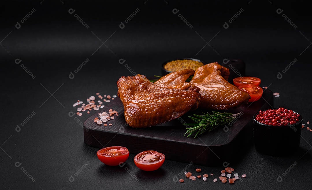 Deliciosas asas de frango grelhado com especiarias e ervas em um fundo escuro de concreto