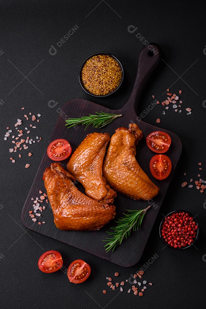 Deliciosas asas de frango grelhado com especiarias e ervas em um fundo escuro de concreto