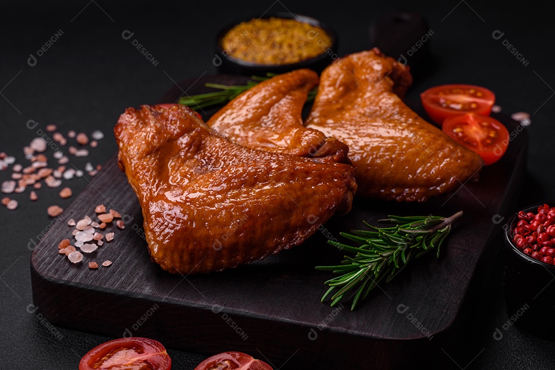 Deliciosas asas de frango grelhado com especiarias e ervas em um fundo escuro de concreto