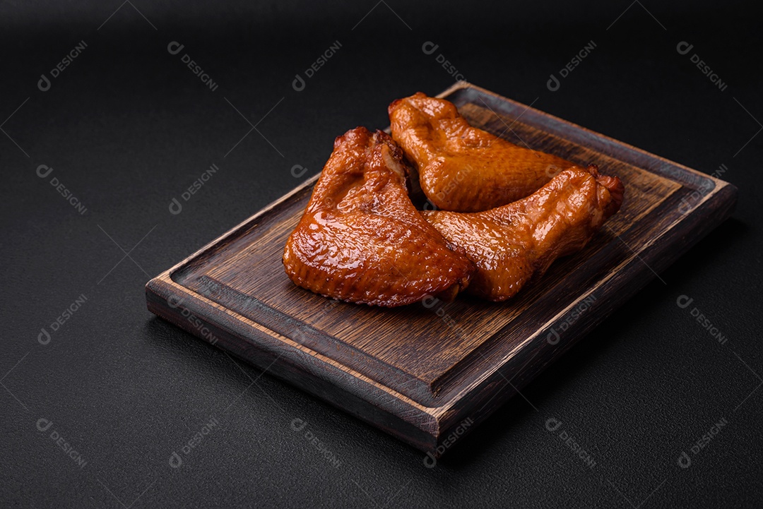 Deliciosas asas de frango grelhado com especiarias e ervas em um fundo escuro de concreto
