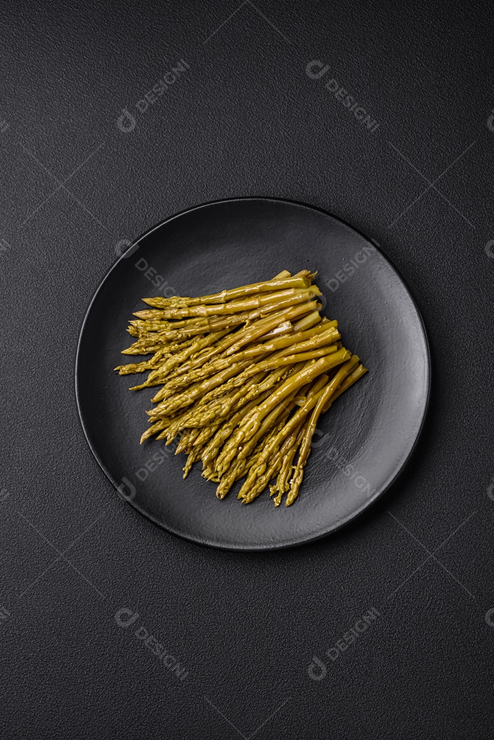 Raminhos de deliciosos espargos enlatados em uma placa de cerâmica preta sobre um fundo escuro de concreto
