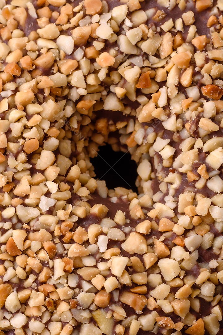 Delicioso donut com recheio de creme e nozes em um fundo escuro de concreto. Comida doce