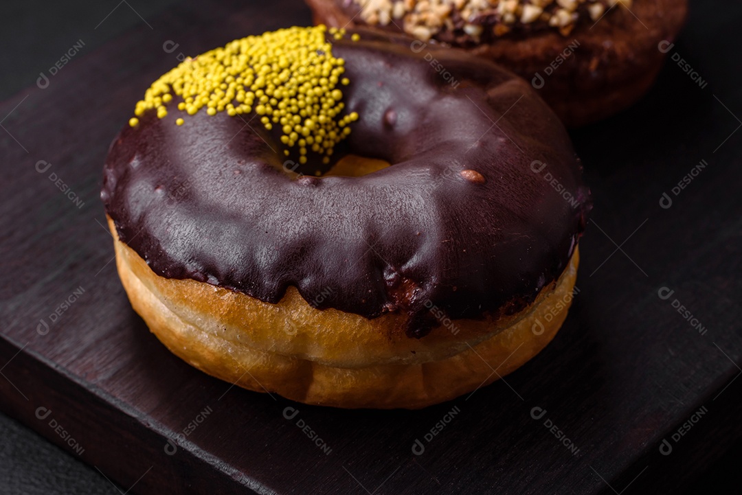 Delicioso donut com recheio de creme e nozes em um fundo escuro de concreto. Comida doce