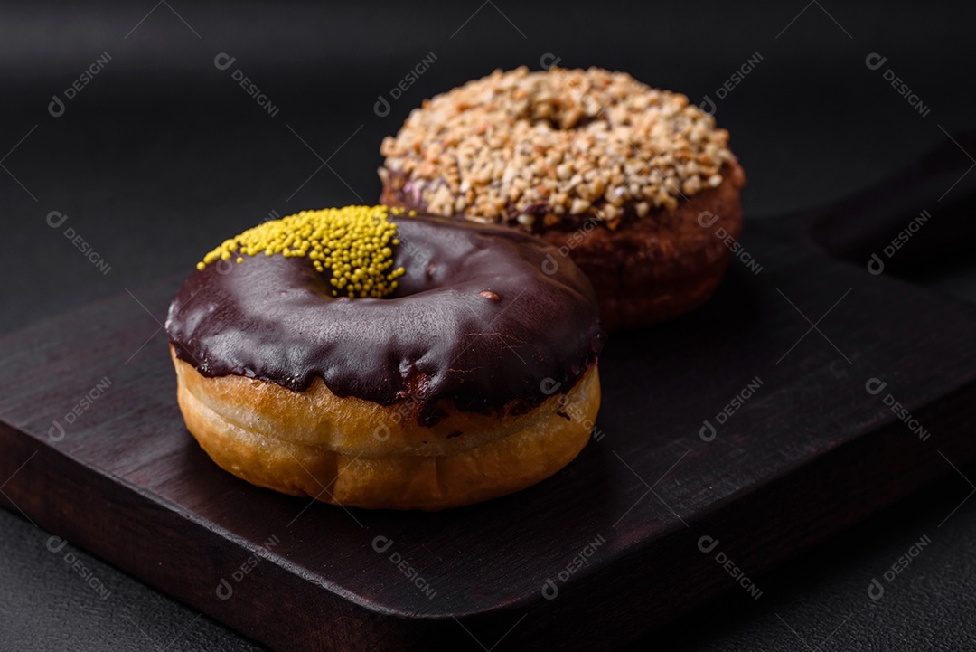 Delicioso donut com recheio de creme e nozes em um fundo escuro de concreto. Comida doce