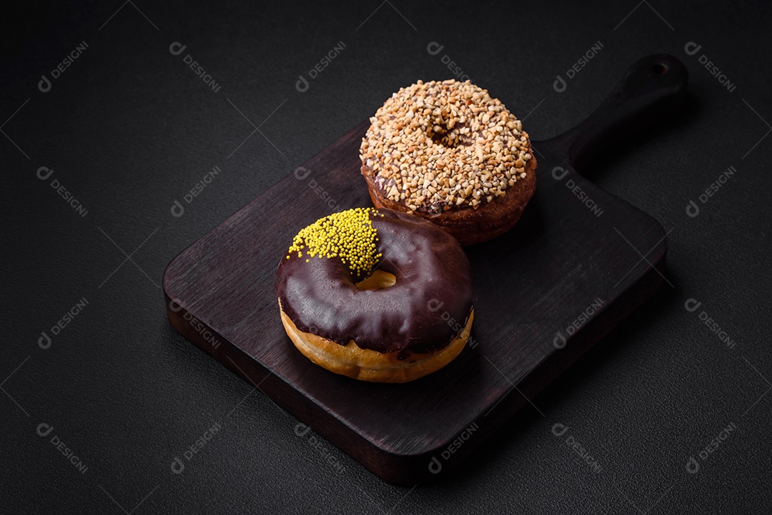 Delicioso donut com recheio de creme e nozes em um fundo escuro de concreto. Comida doce