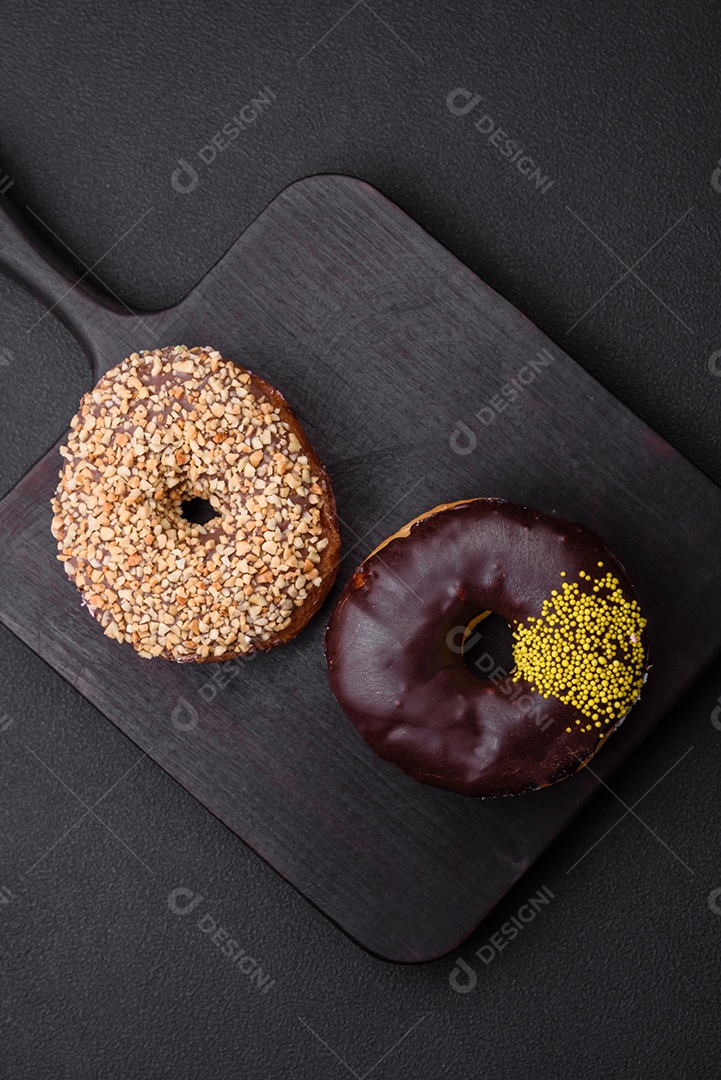 Delicioso donut com recheio de creme e nozes em um fundo escuro de concreto. Comida doce