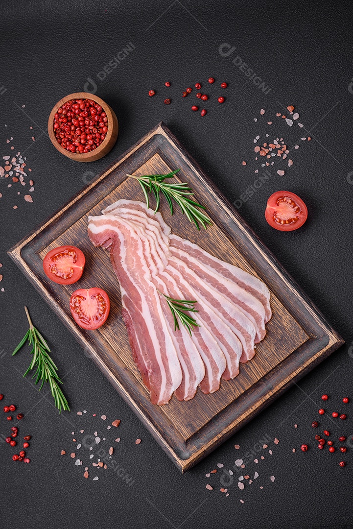Deliciosa pancetta fresca com sal e especiarias cortadas em fatias finas sobre um fundo escuro de concreto