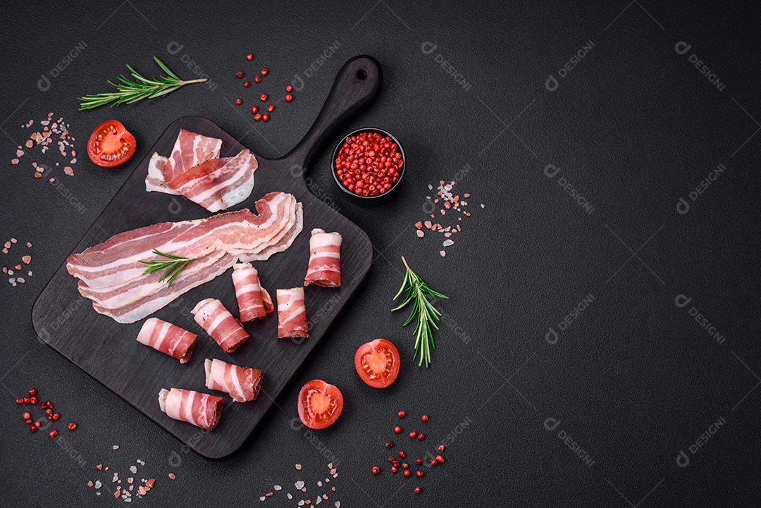 Deliciosa pancetta fresca com sal e especiarias cortadas em fatias finas sobre um fundo escuro de concreto