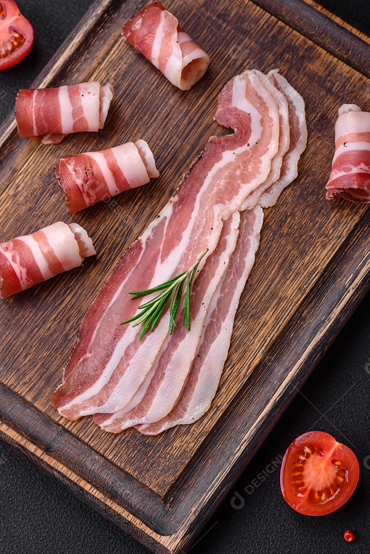 Deliciosa pancetta fresca com sal e especiarias cortadas em fatias finas sobre um fundo escuro de concreto