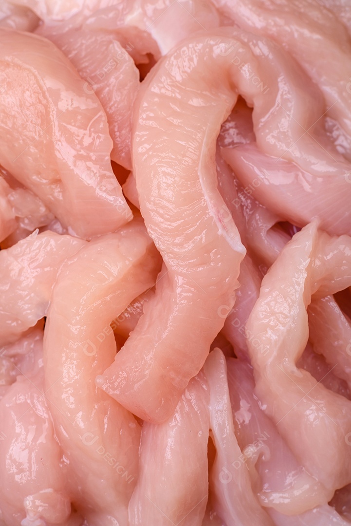 Filé de frango cru cortado em tiras com especiarias e ervas numa tábua de madeira