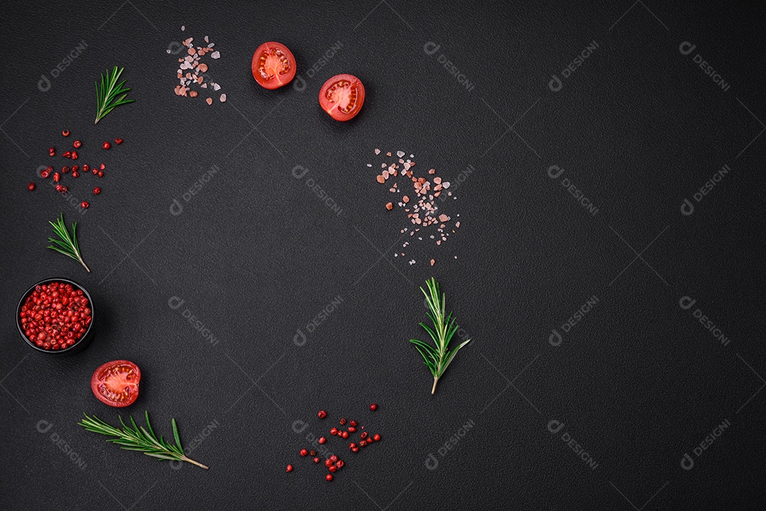 Especiarias, ervas e tomates sobre um fundo escuro.