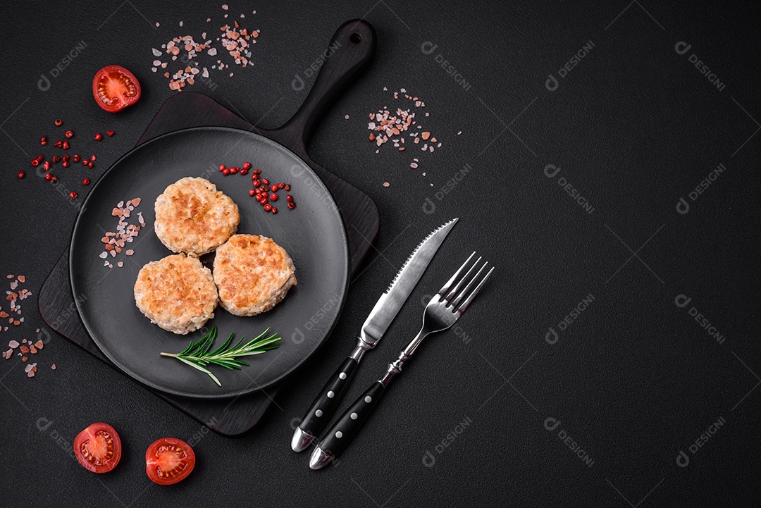 Deliciosas costeletas de frango picado com especiarias e ervas num prato de cerâmica preta