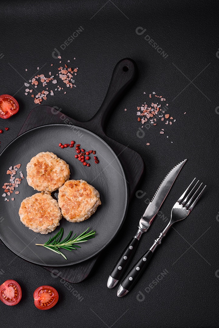 Deliciosas costeletas de frango picado com especiarias e ervas num prato de cerâmica preta