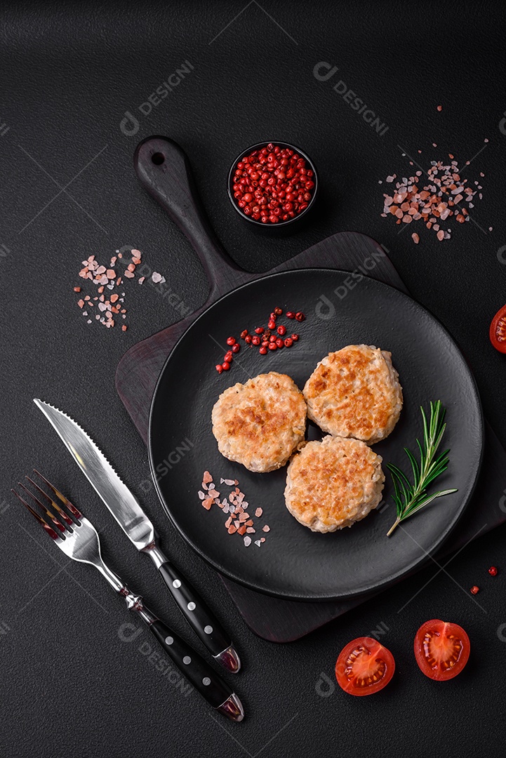 Deliciosas costeletas de frango picado com especiarias e ervas num prato de cerâmica preta