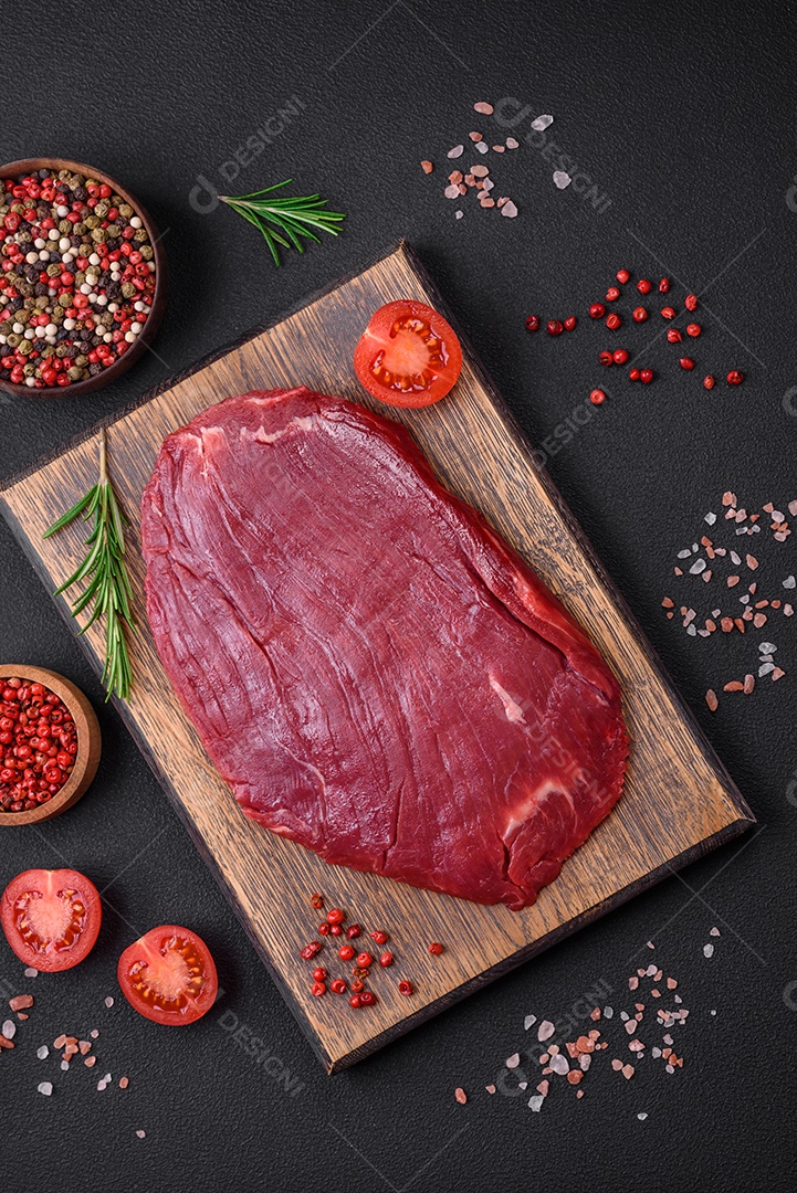 Carne crua fresca com sal, especiarias e ervas sobre um fundo escuro de concreto