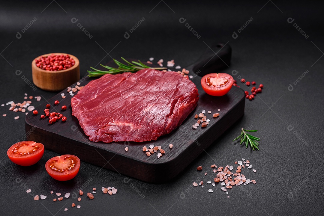 Carne crua fresca com sal, especiarias e ervas sobre um fundo escuro de concreto