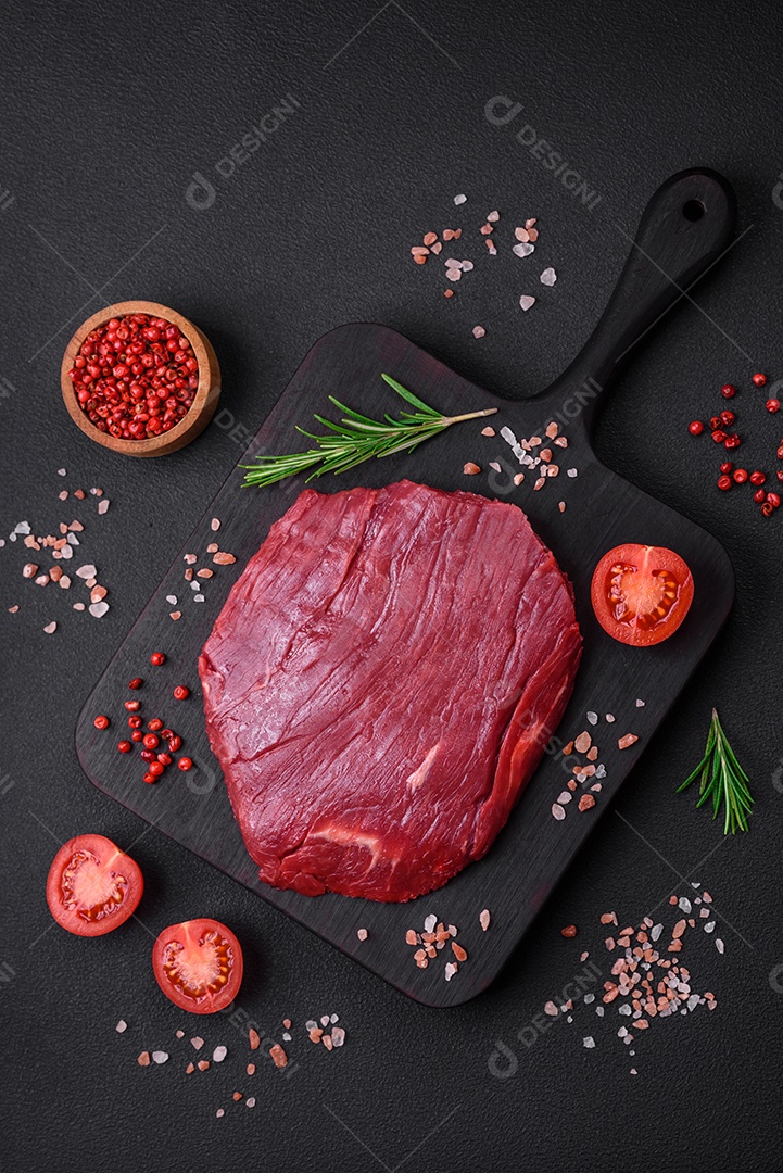 Carne crua fresca com sal, especiarias e ervas sobre um fundo escuro de concreto