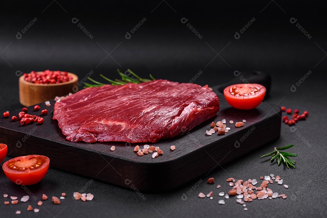 Carne crua fresca com sal, especiarias e ervas sobre um fundo escuro de concreto