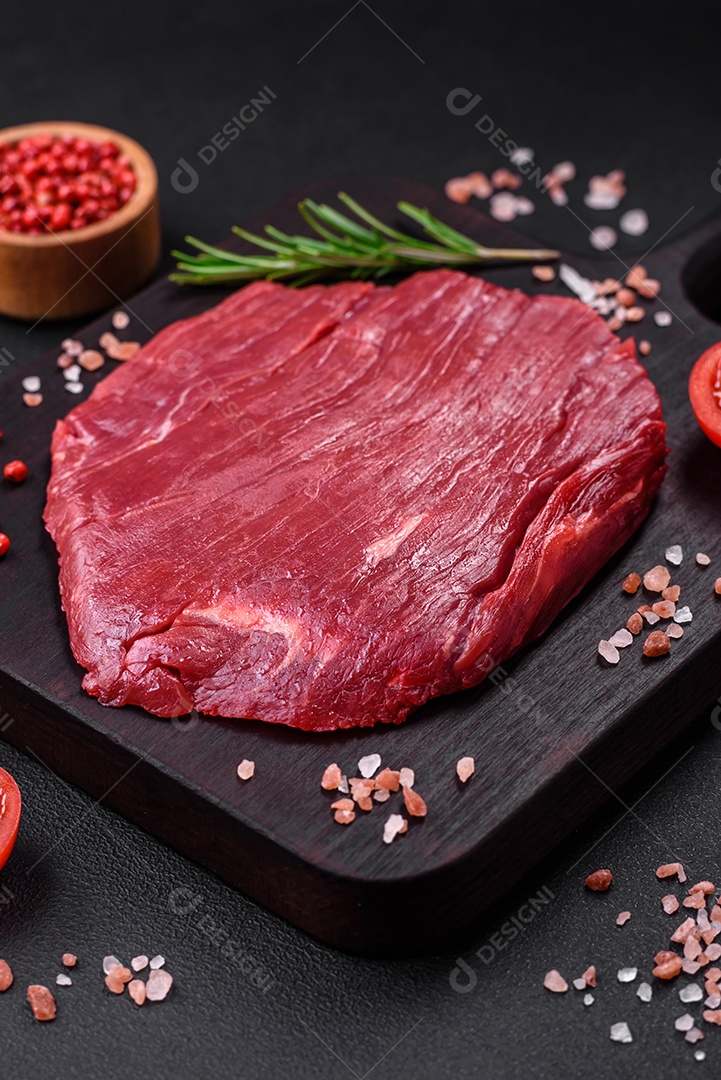 Carne crua fresca com sal, especiarias e ervas sobre um fundo escuro de concreto