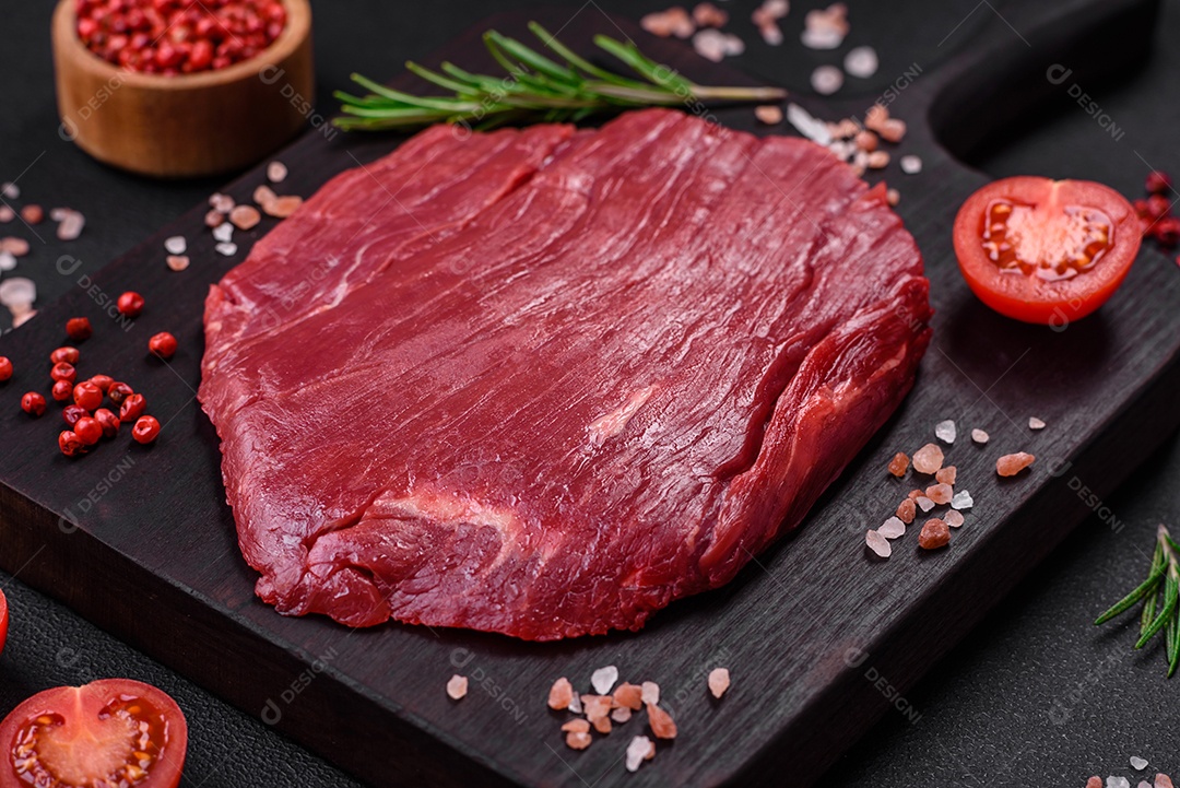 Carne crua fresca com sal, especiarias e ervas sobre um fundo escuro de concreto
