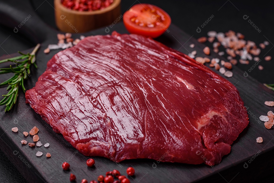 Carne crua fresca com sal, especiarias e ervas sobre um fundo escuro de concreto