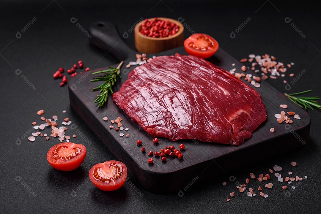 Carne crua fresca com sal, especiarias e ervas sobre um fundo escuro de concreto