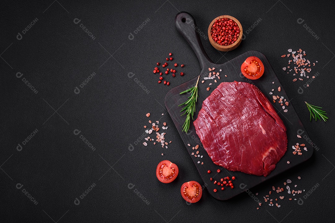 Carne crua fresca com sal, especiarias e ervas sobre um fundo escuro de concreto