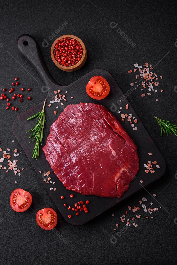 Carne crua fresca com sal, especiarias e ervas sobre um fundo escuro de concreto