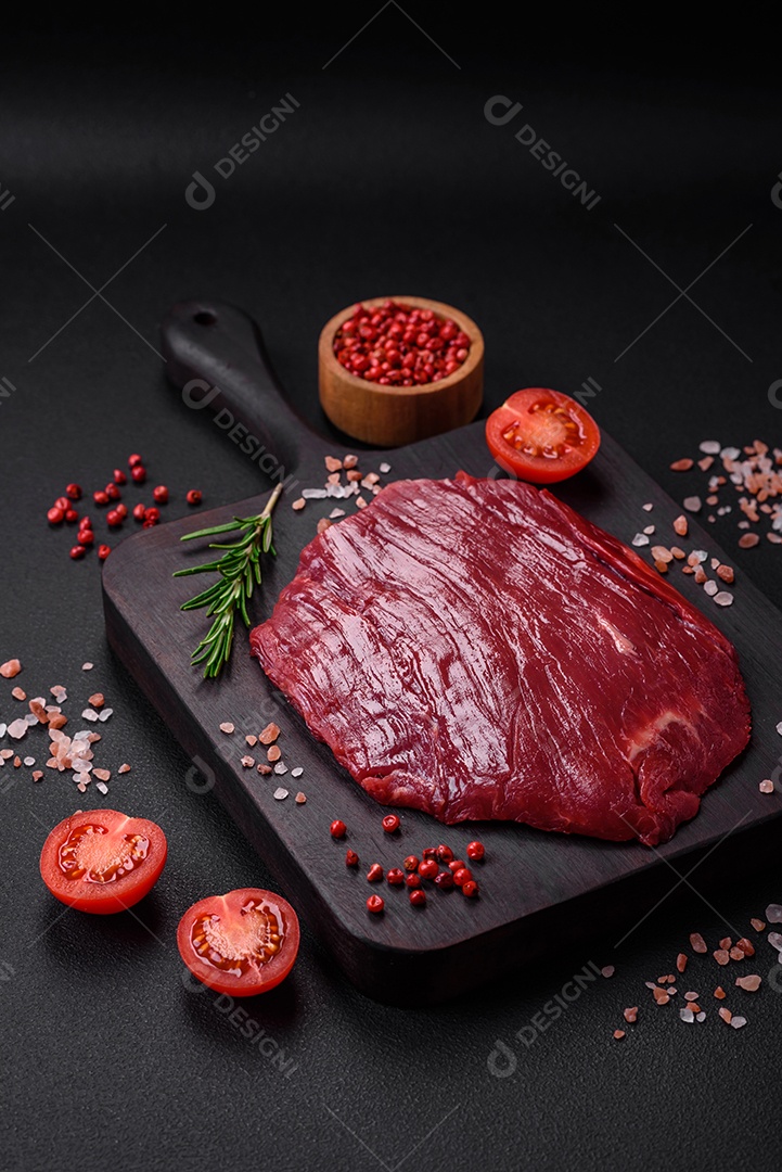 Carne crua fresca com sal, especiarias e ervas sobre um fundo escuro de concreto