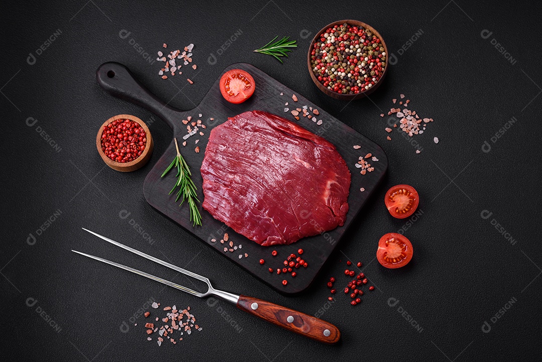 Carne crua fresca com sal, especiarias e ervas sobre um fundo escuro de concreto