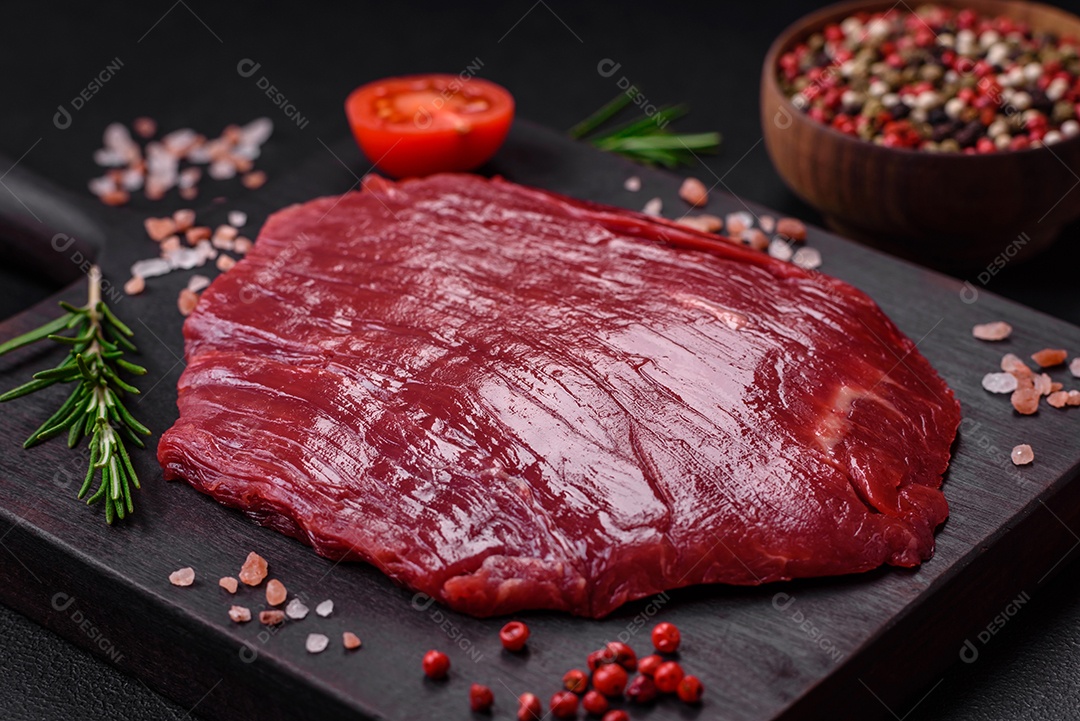 Carne crua fresca com sal, especiarias e ervas sobre um fundo escuro de concreto
