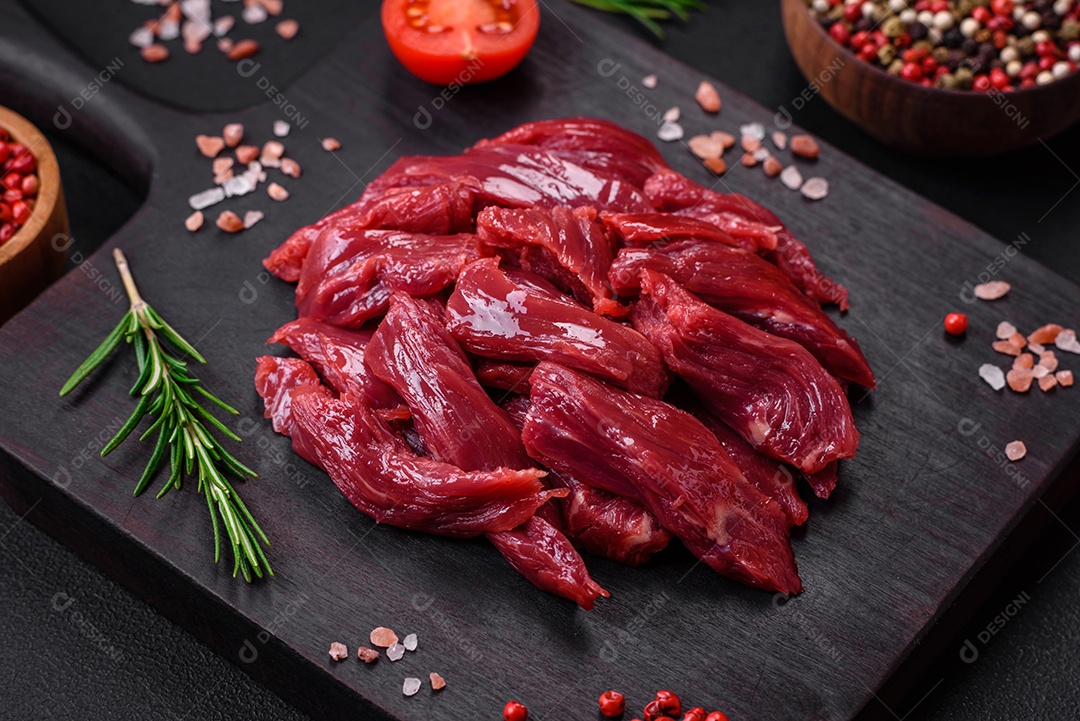 Carne crua fresca com sal, especiarias e ervas sobre um fundo escuro de concreto