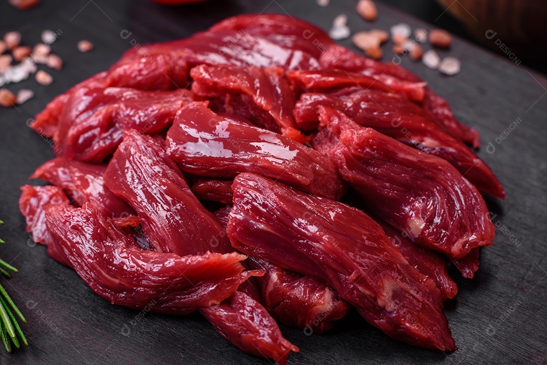 Carne crua fresca com sal, especiarias e ervas sobre um fundo escuro de concreto