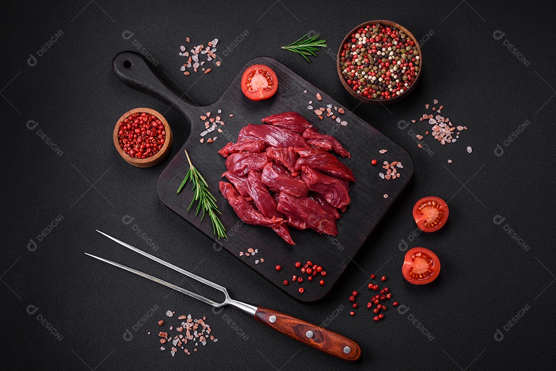 Carne crua fresca com sal, especiarias e ervas sobre um fundo escuro de concreto