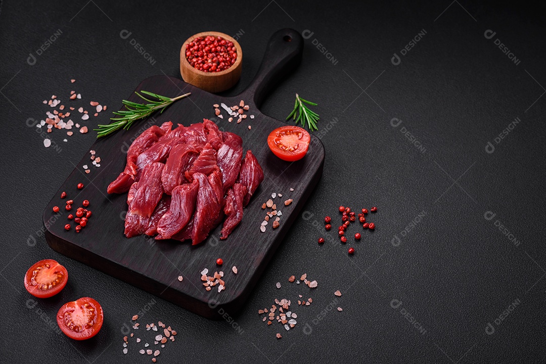 Carne crua fresca com sal, especiarias e ervas sobre um fundo escuro de concreto