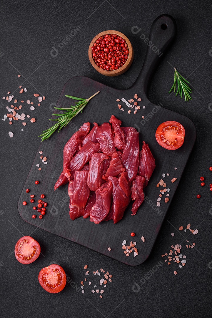 Carne crua fresca com sal, especiarias e ervas sobre um fundo escuro de concreto