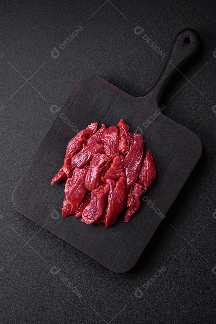 Carne crua fresca com sal, especiarias e ervas sobre um fundo escuro de concreto