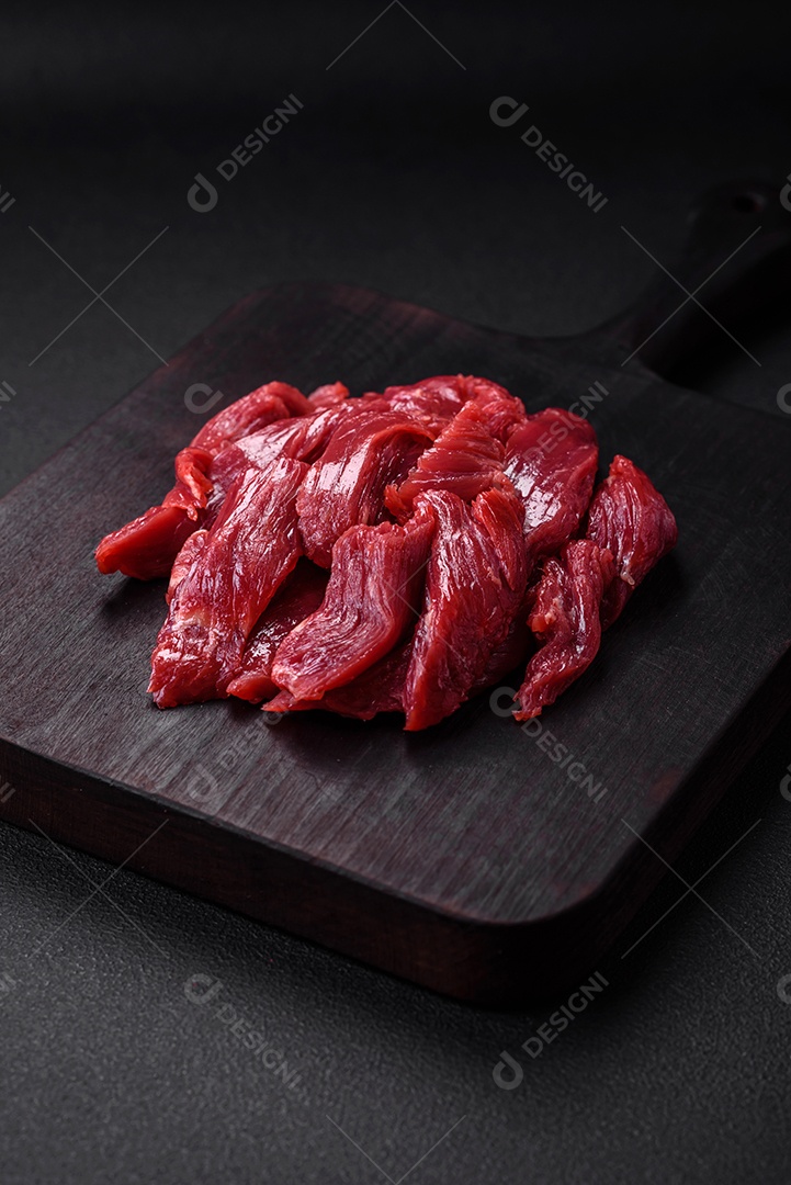 Carne crua fresca com sal, especiarias e ervas sobre um fundo escuro de concreto