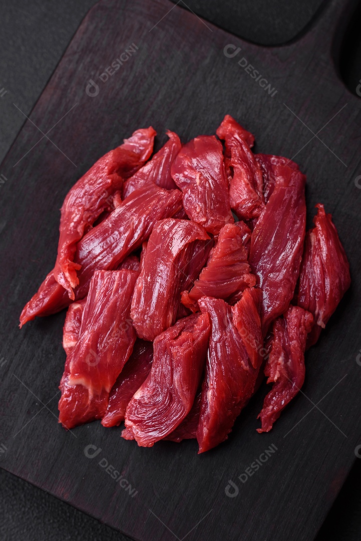 Carne crua fresca com sal, especiarias e ervas sobre um fundo escuro de concreto