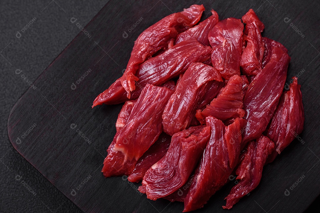 Carne crua fresca com sal, especiarias e ervas sobre um fundo escuro de concreto