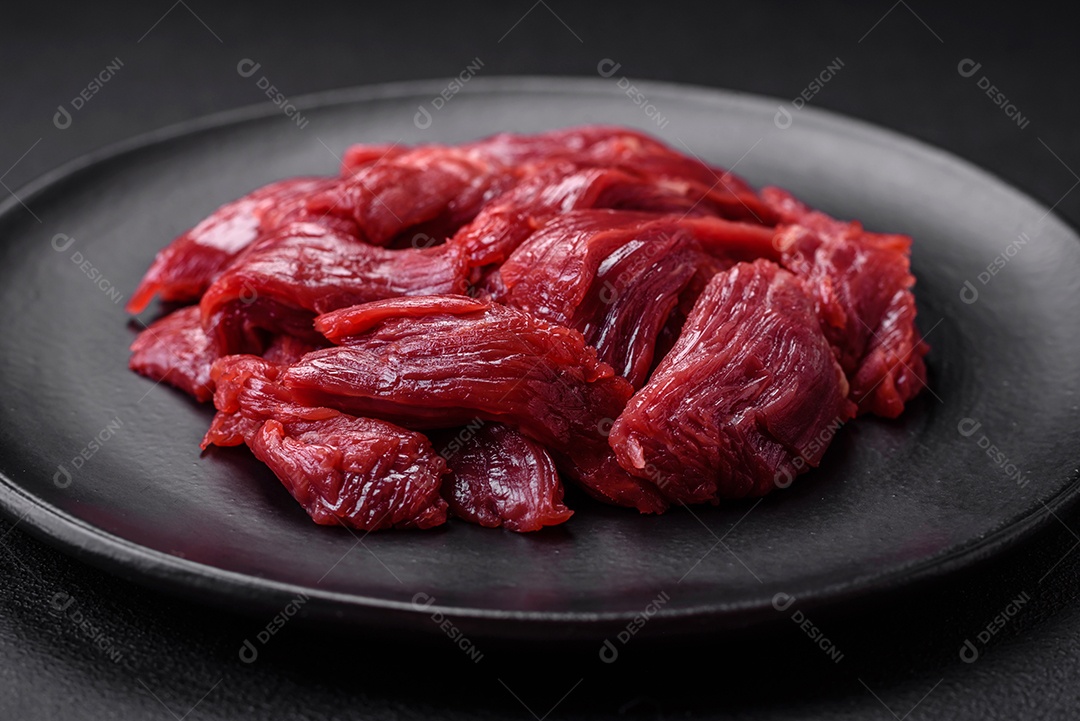 Carne crua fresca com sal, especiarias e ervas sobre um fundo escuro de concreto