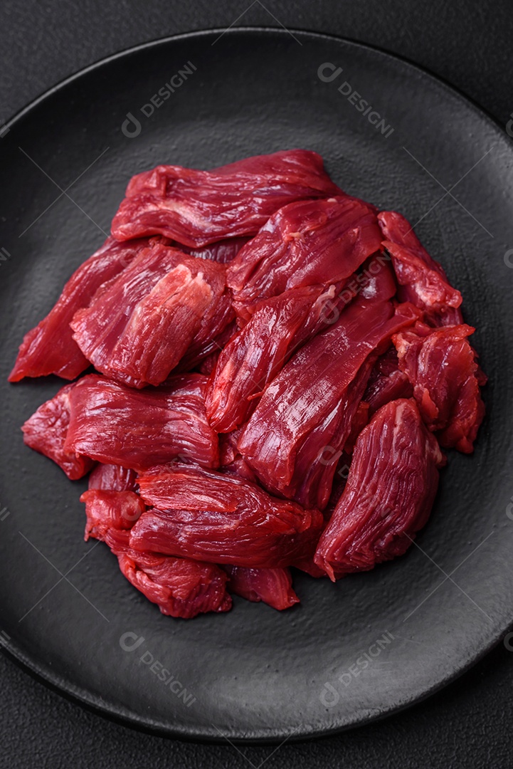 Carne crua fresca com sal, especiarias e ervas sobre um fundo escuro de concreto