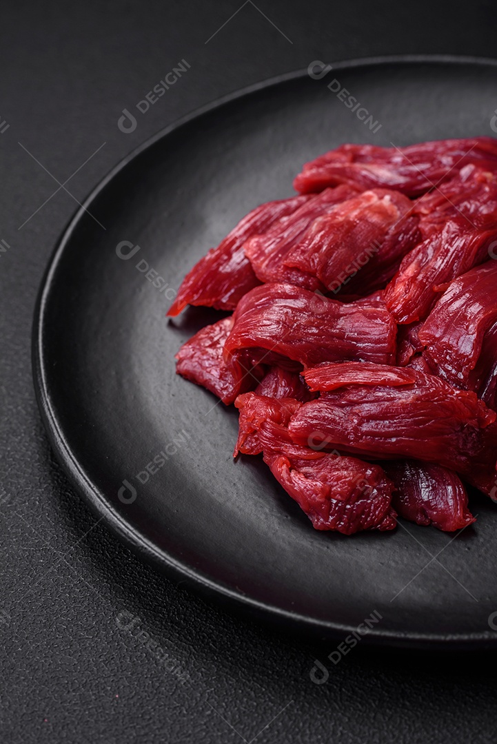 Carne crua fresca com sal, especiarias e ervas sobre um fundo escuro de concreto