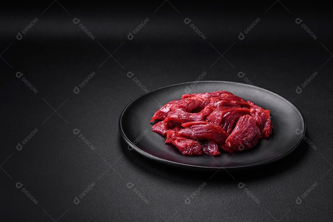 Carne crua fresca com sal, especiarias e ervas sobre um fundo escuro de concreto