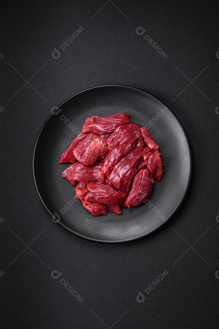 Carne crua fresca com sal, especiarias e ervas sobre um fundo escuro de concreto