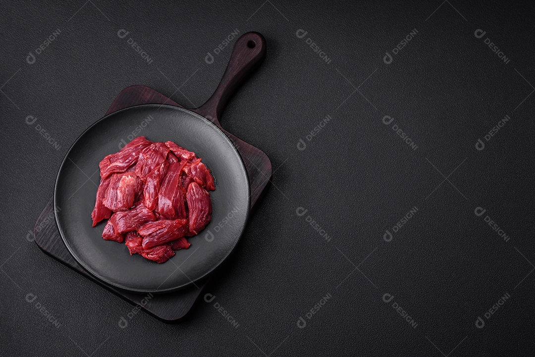 Carne crua fresca com sal, especiarias e ervas sobre um fundo escuro de concreto