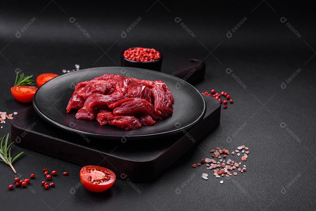 Carne crua fresca com sal, especiarias e ervas sobre um fundo escuro de concreto